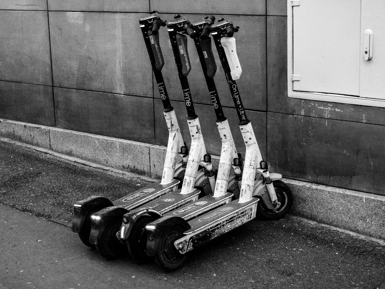 A group of electric scooters parked against a building wall, highlighting urban transportation.